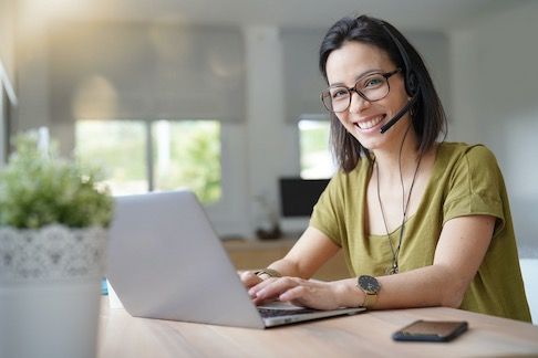 Call center female agent with headset by laptop working from home