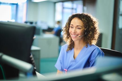 Smiling girl with curly hair answering calls in healthcare verticals environment with hospital clothes and headset