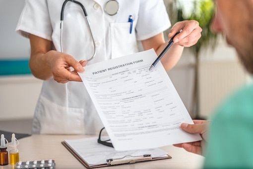 Nurse handing patient registration form and pen to man